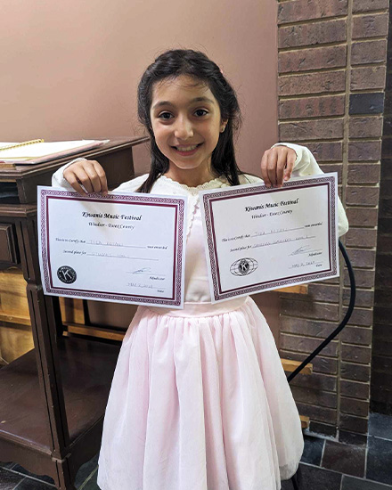 young musician holding up certificates